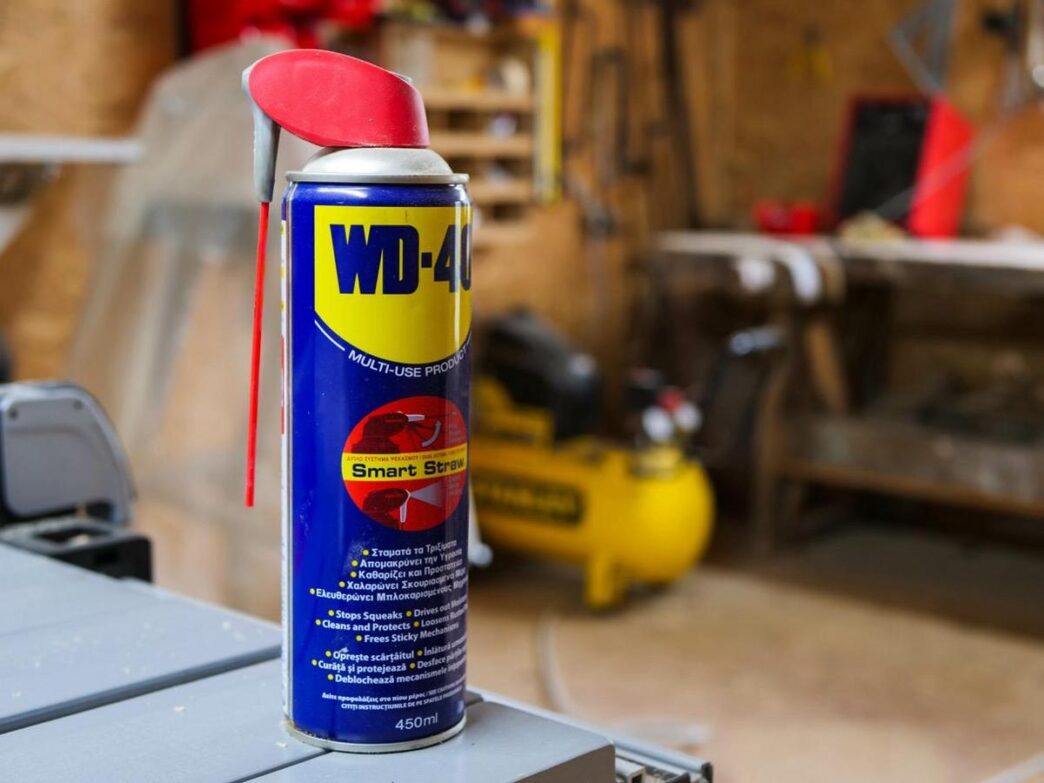 Close-up of a vintage WD-40 can, sparkling mist, surrounded by household tools.