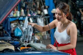 Mechanic performing oil change on modern sedan in a serene, sunlit workshop.