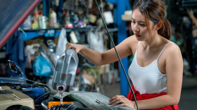 Mechanic performing oil change on modern sedan in a serene, sunlit workshop.